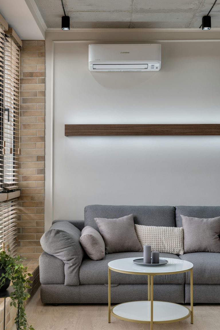 A stylish living room featuring a gray sofa, air conditioner, and minimalist decor for a cozy atmosphere.